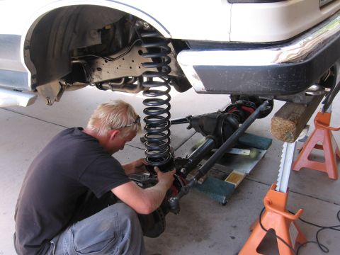 1990 Ford Bronco - Mechanic works on the front axle and suspension of a 1990 Ford Bronco.