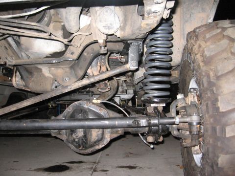 1990 Ford Bronco - This image shows the undercarriage of a modified off-road vehicle, focusing on the suspension and drivetrain components.