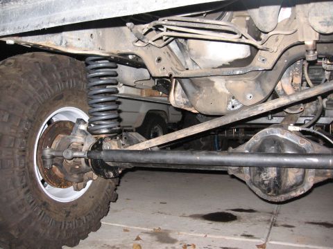 1990 Ford Bronco - Close-up of a vehicle's suspension and axle system, with another vehicle visible in the background.