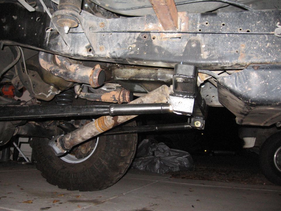 Undercarriage view of a vehicle's suspension and exhaust system, showing a large tire
