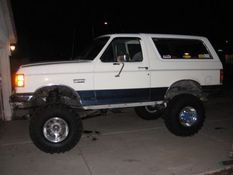 1990 Ford Bronco - This lifted 1990 Ford Bronco is parked outside at night, showing its side profile.