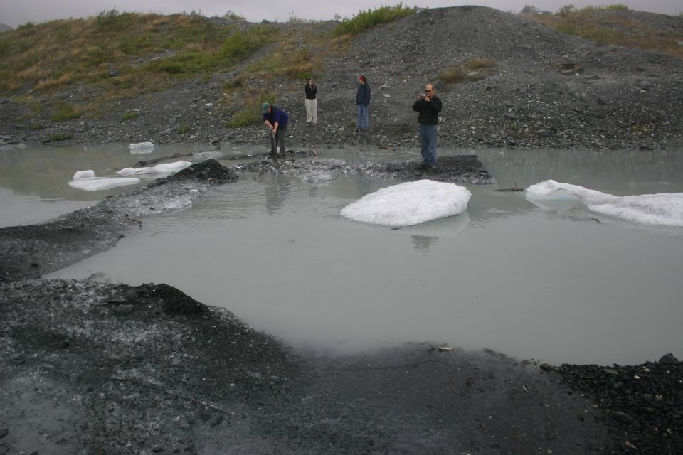Glacial meltwater with ice chunks and people on a rocky shore