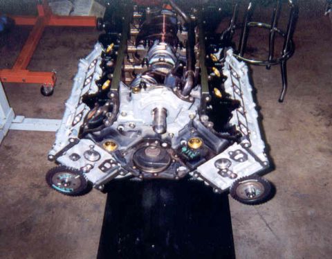 1992 Ford Crown Victoria - Overhead view of a partially assembled overhead-cam V8 short block on an engine stand in a garage, looking down the open valley at the inst…