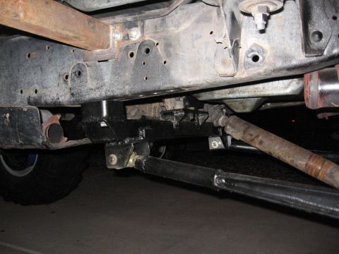 1990 Ford Bronco - Close-up of a vehicle's undercarriage, highlighting suspension modifications and a large tire.