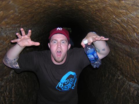 1995 Ford Probe - A person makes a startled face while holding a bottle of water in a rough-walled tunnel.