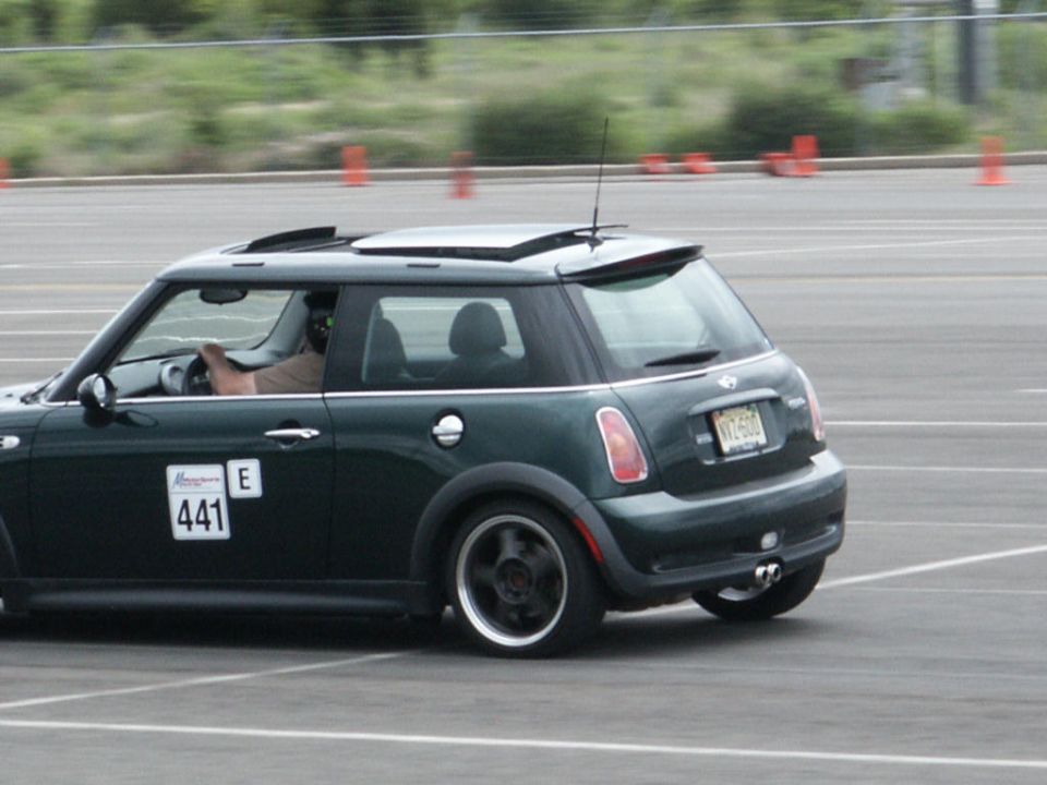 Dark green Mini Cooper with racing numbers 441 and E on the door, driving on a track