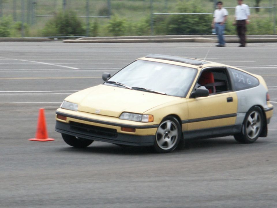 Yellow and grey Honda CRX with a sunroof and racing numbers on the rear quarter panel