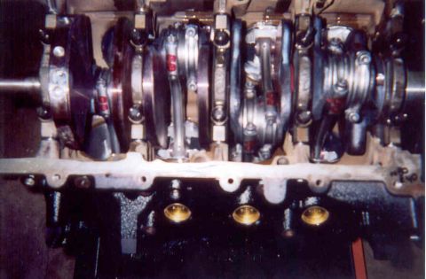 1992 Ford Crown Victoria - Bottom-end view into an inverted V8 block during assembly, showing the crankshaft with counterweights, H-beam connecting rods marked in red…