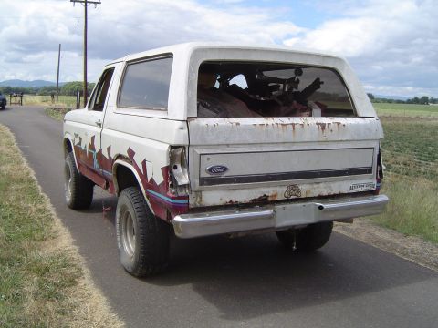 1955 Ford F-100 - This weathered Ford Bronco, likely from the 1980s, is parked on the side of a rural road.