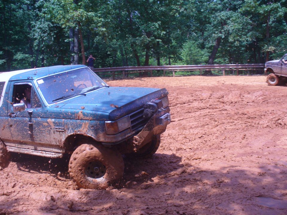 Blue Ford Bronco stuck in mud, another truck in background