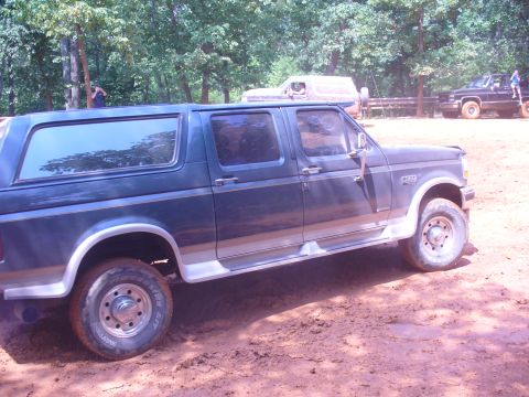 1996 Ford Bronco - A dark blue Ford Bronco with tan trim is seen from the side on a dirt path.