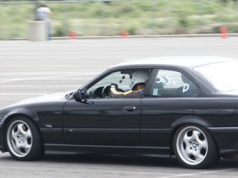 2001 Mercury Grand Marquis - A black coupe with racing drivers is captured in motion on a track.