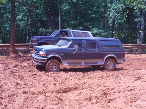 1996 Ford Bronco - Two Ford Broncos navigate a muddy trail during an off-road excursion.