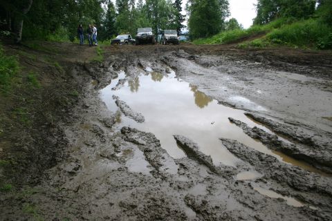 2003 Jeep TJ - Off-road vehicles navigate a challenging muddy terrain with deep ruts and water.