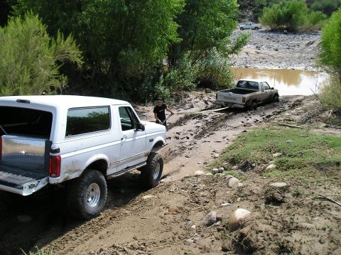 1993 Ford Bronco - A 1993 Ford Bronco assists a stuck Toyota truck out of a muddy embankment near a body of water.