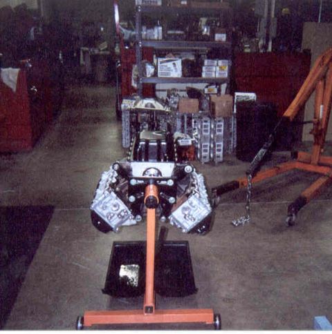 1992 Ford Crown Victoria - Assembled V8 short block mounted on an orange engine stand in a shop, viewed head-on with the cylinder heads bolted on, valley open and dri…