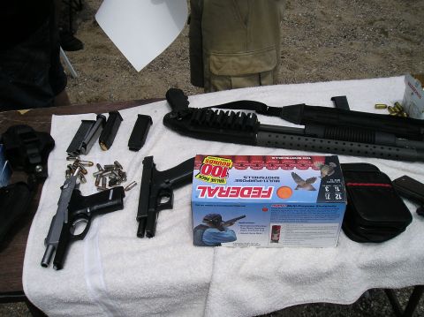1993 Ford Bronco - Table display of firearms, ammunition, and shotshells, including two handguns and a shotgun.