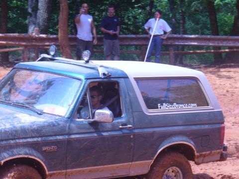 1996 Ford Bronco - 1996 Ford Bronco navigating an off-road trail with a driver visible inside.
