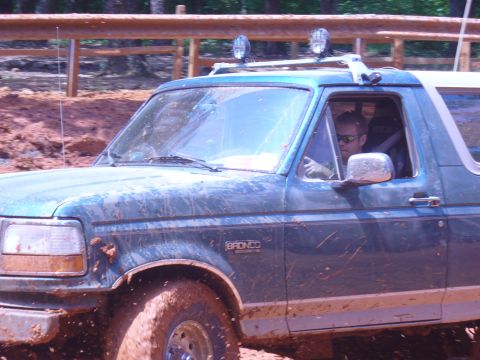 1996 Ford Bronco - A driver navigates a muddy trail in a 1996 Ford Bronco, kicking up dirt as it goes.