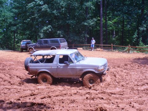 1996 Ford Bronco - A 1996 Ford Bronco navigates a muddy off-road trail with other vehicles present.