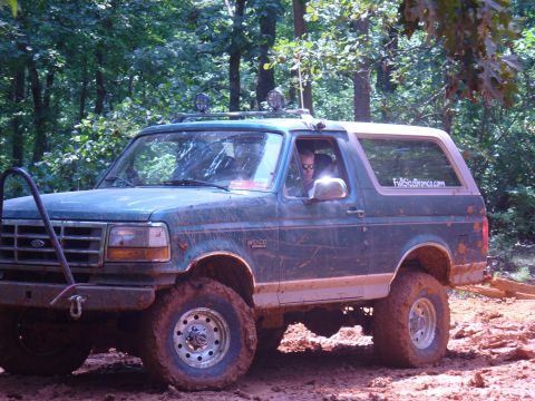 1996 Ford Bronco - This 1996 Ford Bronco navigates a challenging muddy off-road course surrounded by dense forest foliage.