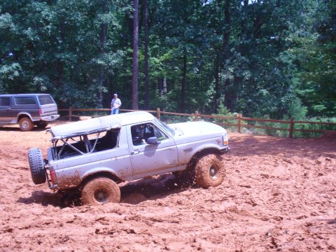 1996 Ford Bronco - This 1996 Ford Bronco tackles a challenging muddy terrain, with another SUV visible in the background.