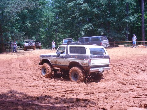 1996 Ford Bronco - This Ford Bronco is navigating a muddy off-road course with other vehicles present.