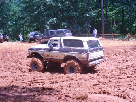 1996 Ford Bronco - This lifted Ford Bronco is deep in the mud during an off-road event, with other vehicles visible in the background.