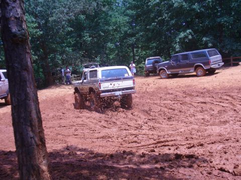 1996 Ford Bronco - Several SUVs navigate a muddy trail during an off-road excursion.