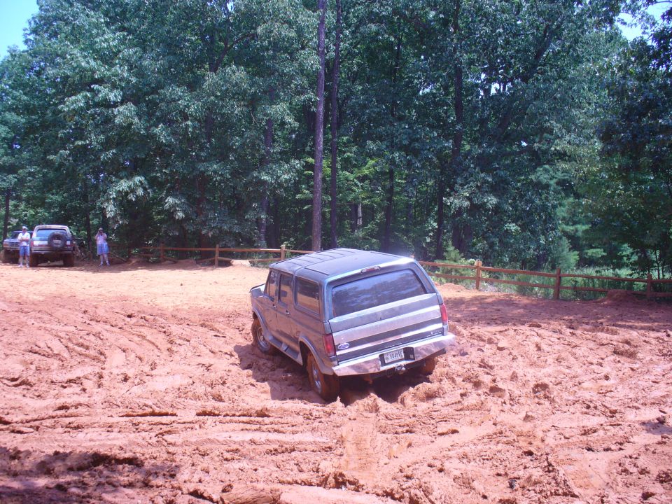 Rear view of a gray Ford Bronco navigating a muddy off-road course