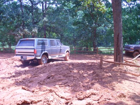 1996 Ford Bronco - A 1996 Ford Bronco navigates a muddy off-road trail, with another vehicle partially visible.