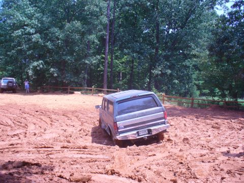 1996 Ford Bronco - A Ford Bronco navigates a muddy trail with another vehicle visible in the background.