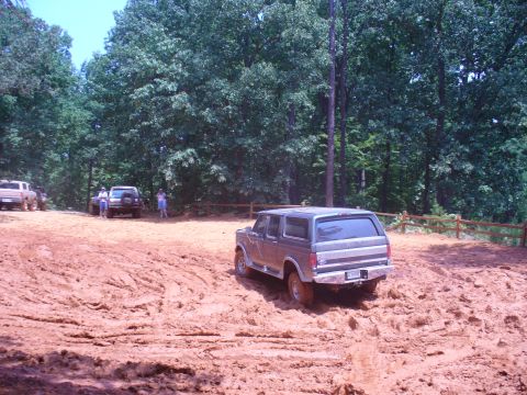 1996 Ford Bronco - An SUV navigates a muddy off-road course with other vehicles visible in the background.