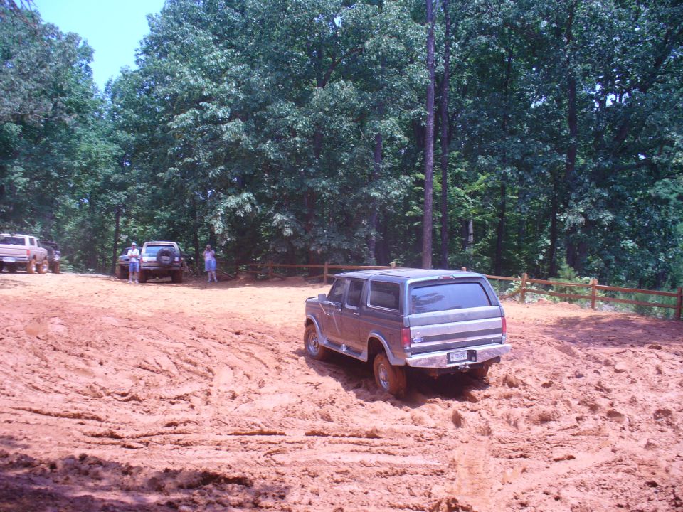 Gray SUV driving through mud, rear view. Appears to be from the 1980s