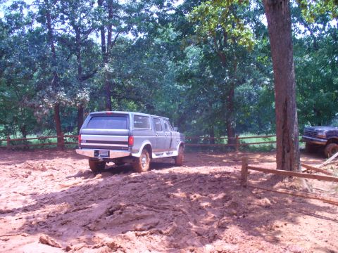1996 Ford Bronco - A gray Ford Bronco with a camper shell navigates a muddy off-road course.