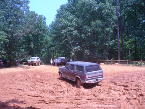 1996 Ford Bronco - Several SUVs, including a Ford Bronco, drive through a muddy off-road course.