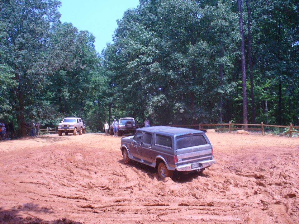 Ford Bronco navigating a muddy track with other SUVs in the background