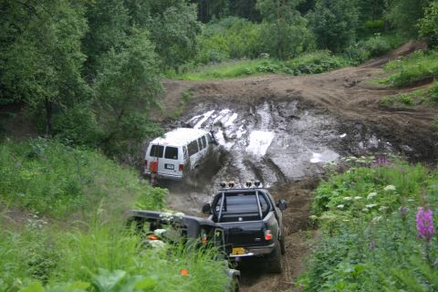 2003 Jeep TJ - Two vehicles attempt to traverse a challenging muddy terrain, with one van visibly struggling in the mire.