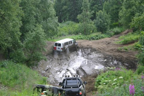 2003 Jeep TJ - Two vehicles struggle through a deep mud pit on a wooded trail.
