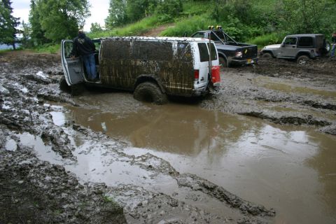 2003 Jeep TJ - Multiple vehicles are stuck in thick mud on an off-road trail.