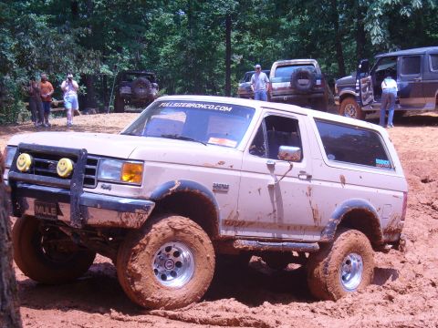1996 Ford Bronco - This Ford Bronco navigates a muddy off-road course with other vehicles in the background.