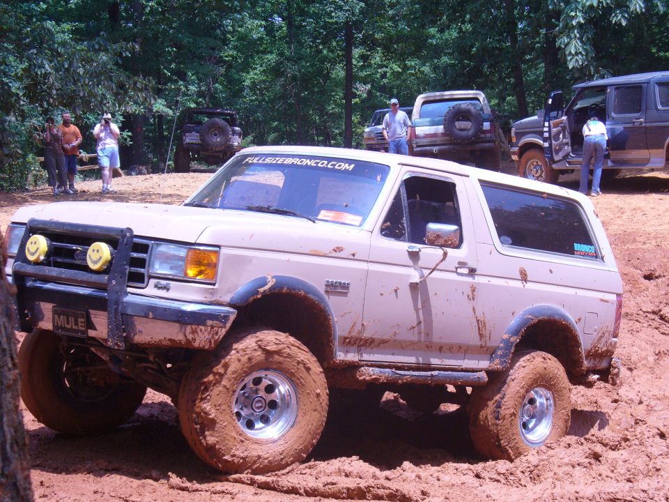 Tan Ford Bronco with "MULE" plate stuck in mud