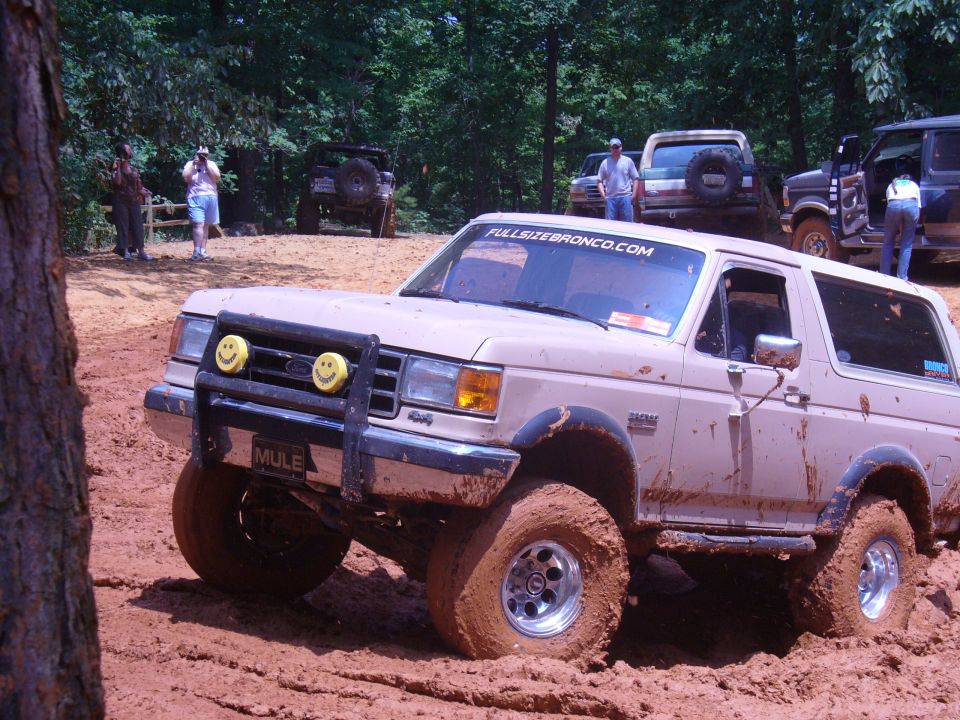 1996 Ford Bronco stuck in mud with other vehicles in background