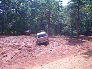 1996 Ford Bronco - A 1996 Ford Bronco navigates a muddy trail in a wooded area.
