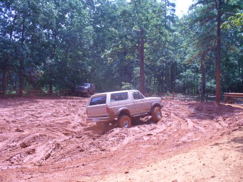 1996 Ford Bronco - A tan SUV navigates a muddy trail with another vehicle visible in the background.