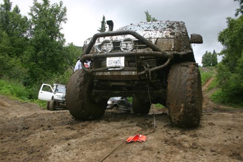 2003 Jeep TJ - This heavily modified off-road vehicle is covered in mud, with a winch visible on the front bumper and large tires.