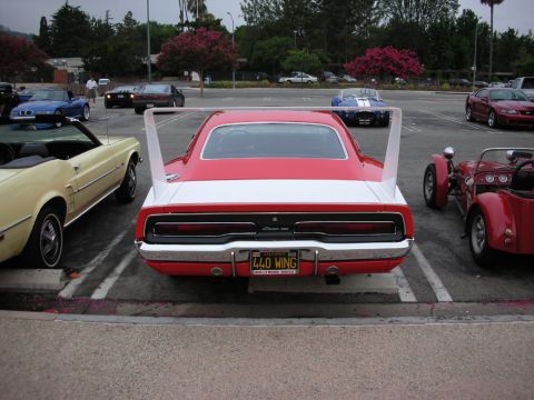 1998 Ford Crown Victoria - Rear view of a red and white winged Dodge Charger Daytona parked at a car show beside a yellow coupe and a red roadster.