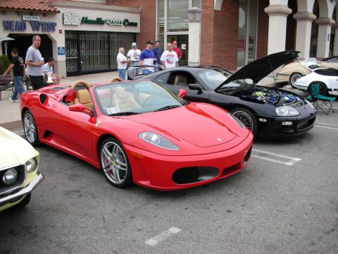 1998 Ford Crown Victoria - red Ferrari F430 Spider with tan interior and silver alloy wheels parked at a curbside car show.