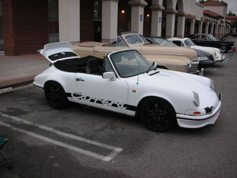 1998 Ford Crown Victoria - white air-cooled Porsche 911 Carrera convertible with black wheels and side Carrera script, top down.