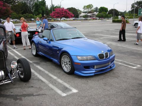 1998 Ford Crown Victoria - bright blue BMW Z3 roadster with a front lip body kit and multi-spoke wheels parked at a car meet.